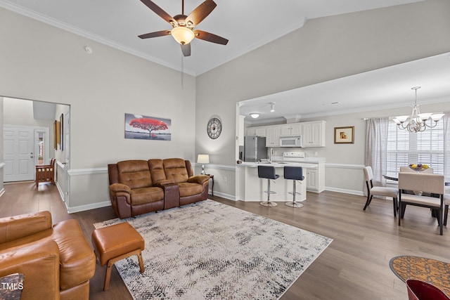 living room featuring a towering ceiling, baseboards, ornamental molding, and wood finished floors