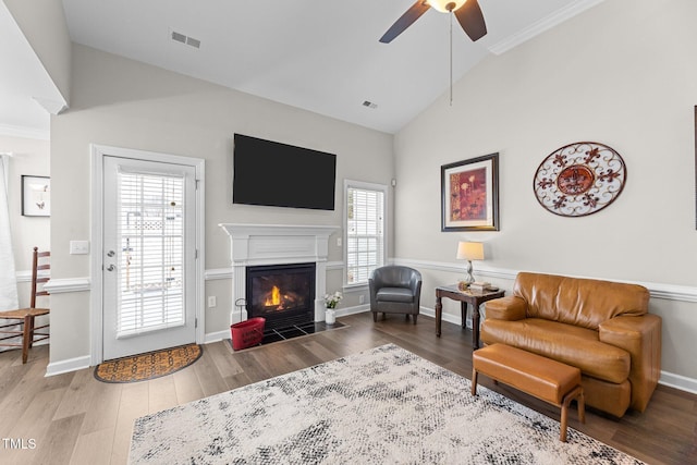 living room featuring high vaulted ceiling, a fireplace with flush hearth, visible vents, and wood finished floors