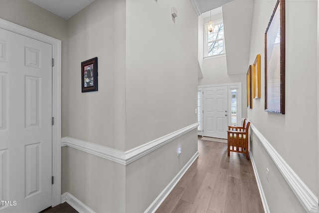 entryway featuring light wood finished floors, a high ceiling, and baseboards