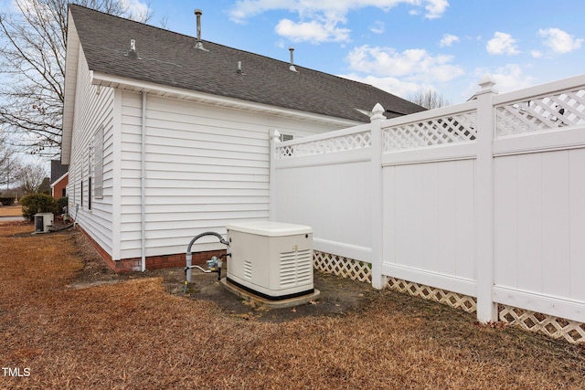 exterior space with central AC unit, a shingled roof, and fence