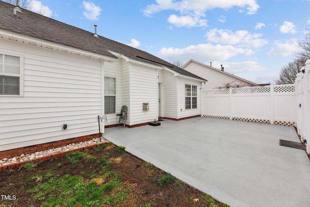 rear view of house with a shingled roof, a patio area, and fence