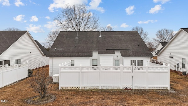 back of house with a shingled roof and fence