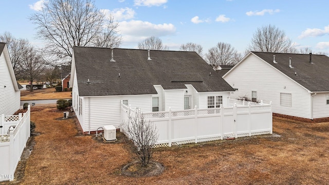 rear view of house with fence and roof with shingles