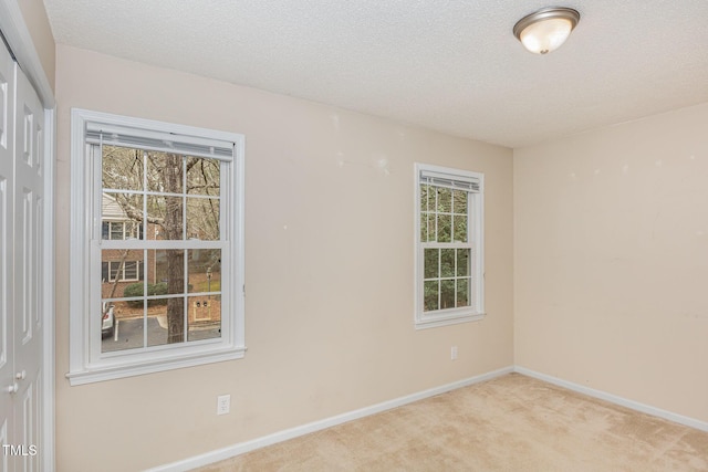 carpeted spare room with a textured ceiling and baseboards