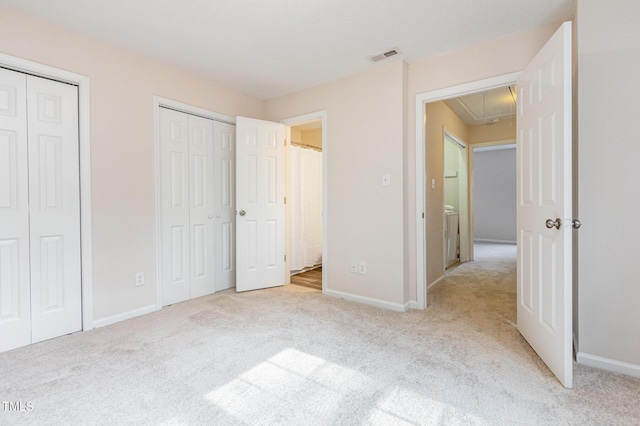 unfurnished bedroom with two closets, light colored carpet, visible vents, attic access, and baseboards