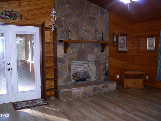 unfurnished living room featuring hardwood / wood-style floors, a fireplace, french doors, and wood walls