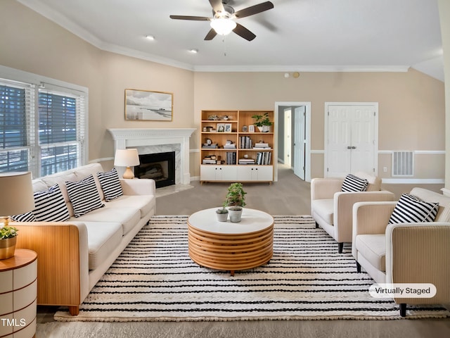 living room with a high end fireplace, ornamental molding, and ceiling fan