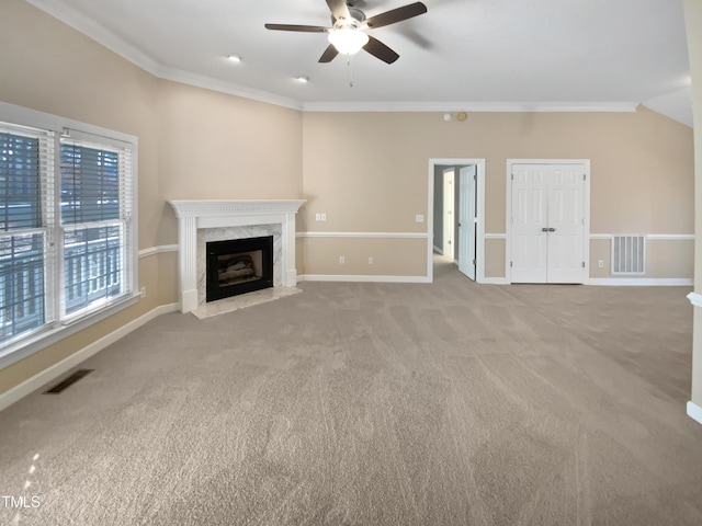 unfurnished living room featuring ceiling fan, light colored carpet, ornamental molding, and a fireplace