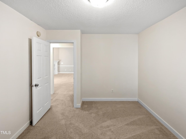 spare room with light carpet and a textured ceiling