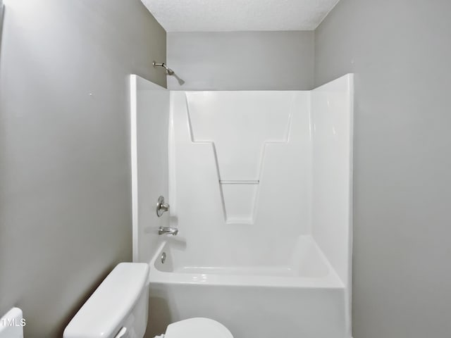 bathroom featuring  shower combination, toilet, and a textured ceiling