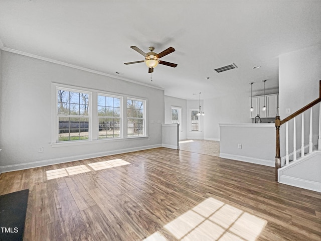 unfurnished living room featuring ornamental molding, ceiling fan with notable chandelier, and hardwood / wood-style floors