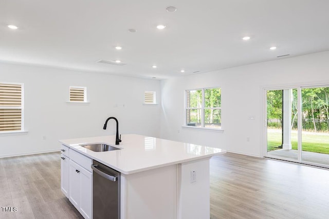 kitchen with a kitchen island with sink, sink, white cabinets, and light wood-type flooring