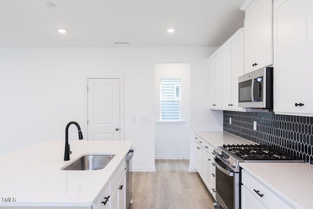 kitchen with white cabinetry, appliances with stainless steel finishes, sink, and backsplash