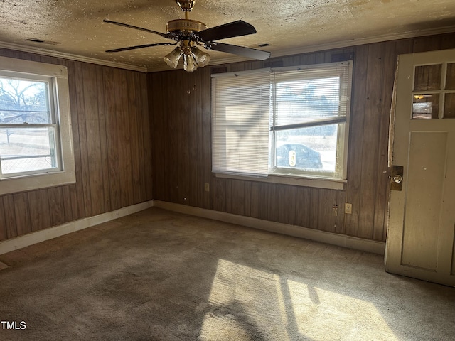 spare room featuring ornamental molding, carpet flooring, a textured ceiling, and wood walls