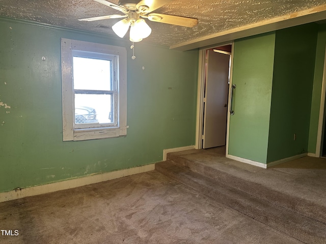 empty room featuring ceiling fan, carpet, and a textured ceiling