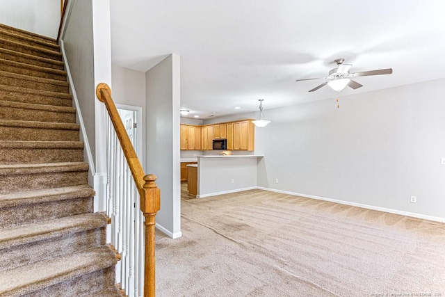 staircase featuring ceiling fan and carpet flooring