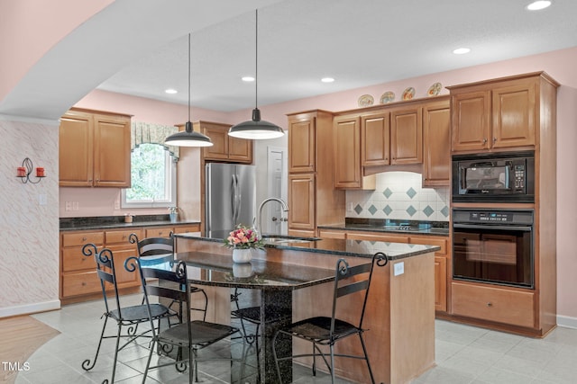 kitchen with sink, hanging light fixtures, a kitchen breakfast bar, black appliances, and a center island with sink