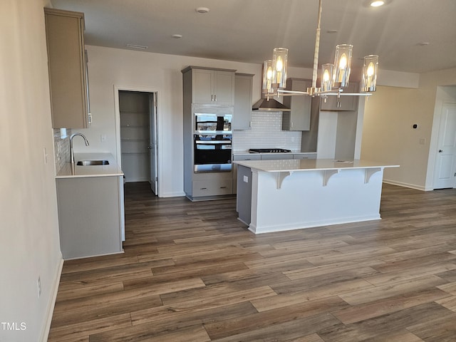 kitchen featuring sink, appliances with stainless steel finishes, gray cabinets, a kitchen island, and pendant lighting