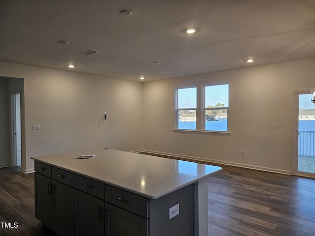 kitchen with dark wood-type flooring, a water view, a healthy amount of sunlight, and a kitchen island