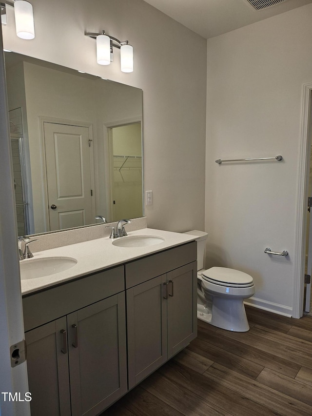 bathroom featuring hardwood / wood-style flooring, vanity, toilet, and walk in shower