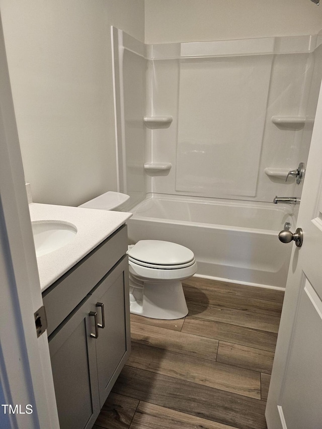 full bathroom featuring hardwood / wood-style flooring, vanity, shower / bathtub combination, and toilet