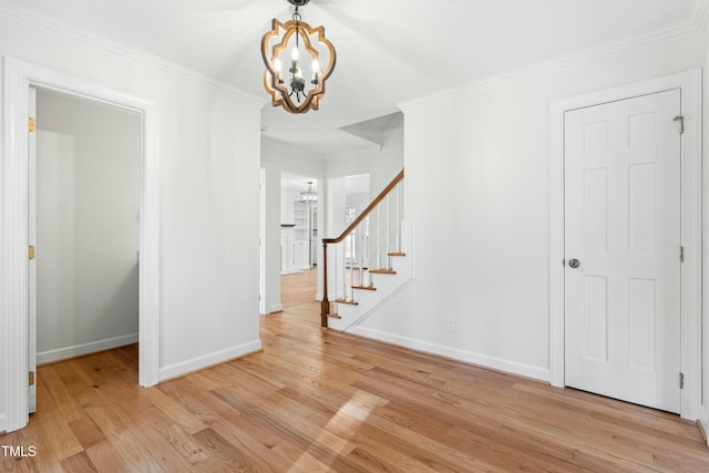 unfurnished room with crown molding, a notable chandelier, and light wood-type flooring