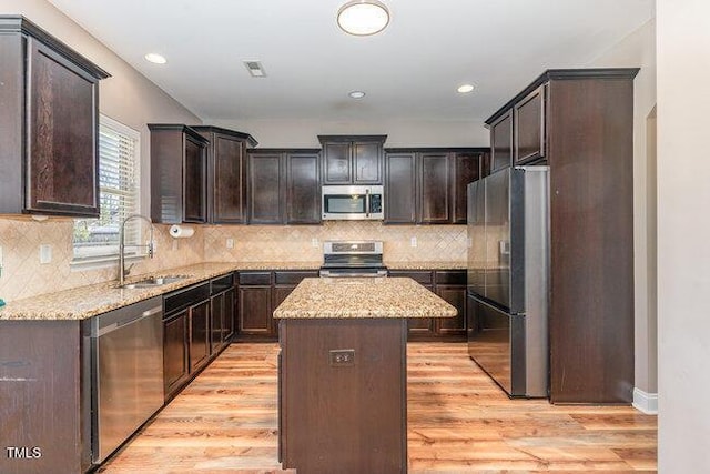 kitchen with appliances with stainless steel finishes, a center island, dark brown cabinetry, and light hardwood / wood-style floors