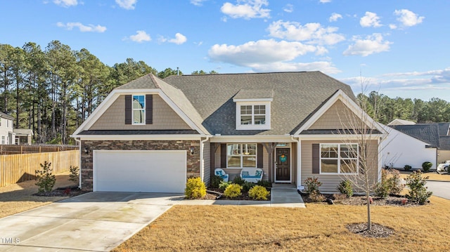 view of front of home with a garage, concrete driveway, stone siding, fence, and a front yard