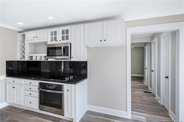 kitchen with white cabinetry, appliances with stainless steel finishes, wood-type flooring, and backsplash