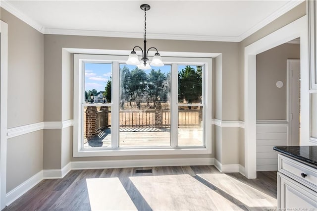 unfurnished dining area with ornamental molding, an inviting chandelier, and dark hardwood / wood-style flooring