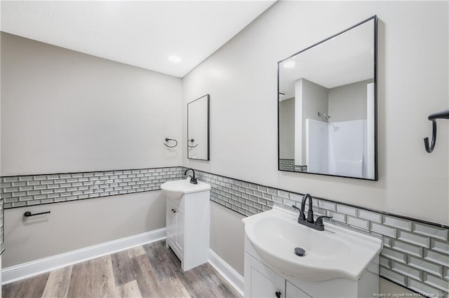 bathroom with hardwood / wood-style flooring, vanity, and a shower