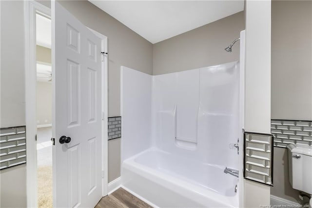 bathroom featuring wood-type flooring, toilet, and shower / bathing tub combination