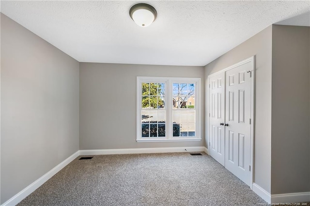 unfurnished bedroom featuring a closet, a textured ceiling, and carpet