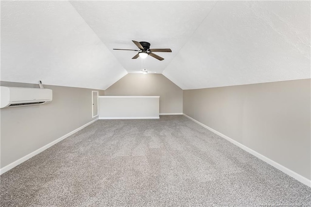 additional living space with lofted ceiling, ceiling fan, a wall unit AC, carpet floors, and a textured ceiling