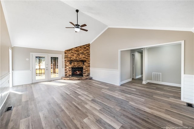 unfurnished living room featuring ceiling fan, wood-type flooring, a stone fireplace, vaulted ceiling, and french doors