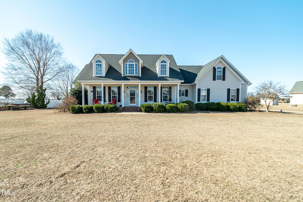 cape cod house featuring a porch and a front yard