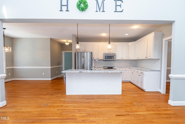 kitchen with stainless steel appliances, decorative light fixtures, an island with sink, and white cabinets