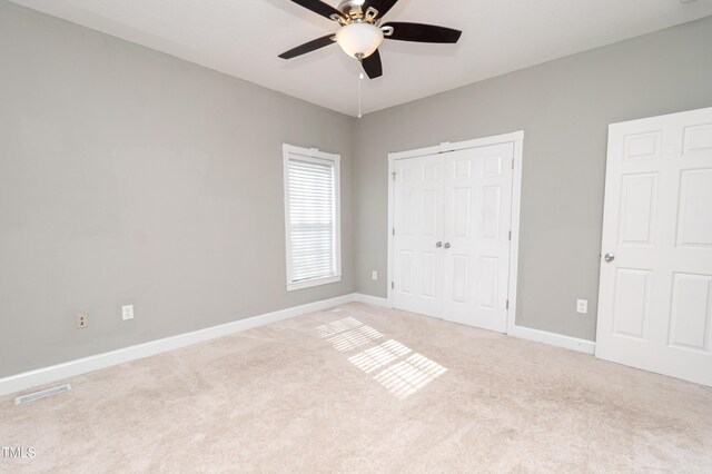 unfurnished bedroom with light colored carpet, a closet, and ceiling fan