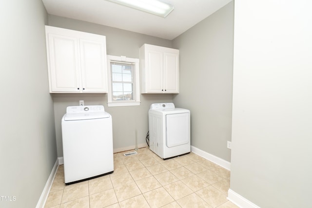 laundry room with cabinets, light tile patterned floors, and washer and dryer