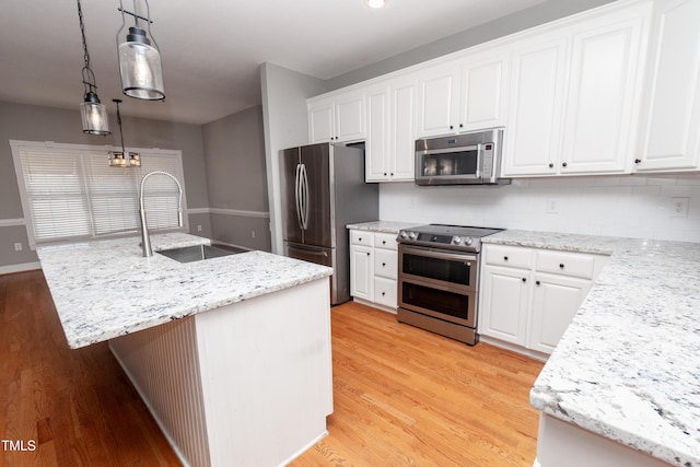 kitchen with sink, decorative light fixtures, a center island with sink, stainless steel appliances, and white cabinets