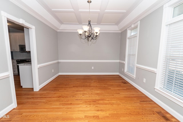 unfurnished dining area featuring a healthy amount of sunlight, coffered ceiling, an inviting chandelier, and light hardwood / wood-style floors