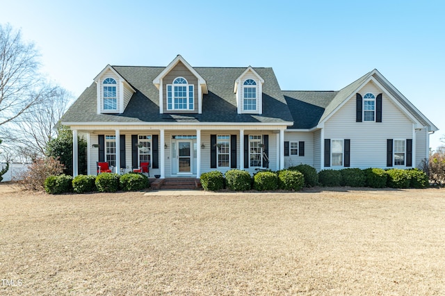 cape cod home with covered porch and a front lawn