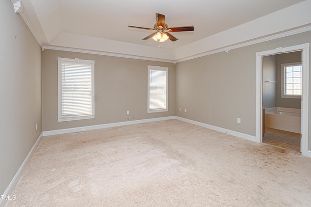 carpeted empty room featuring a raised ceiling, ornamental molding, and ceiling fan