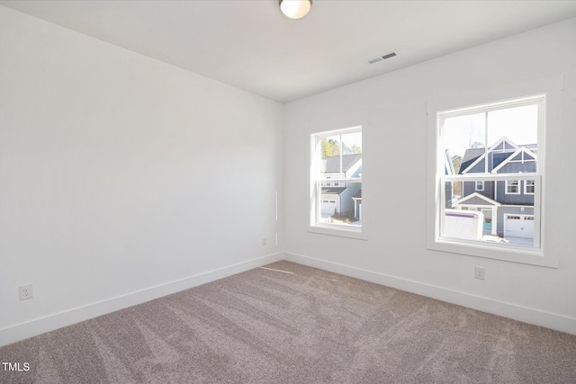 empty room featuring carpet floors, visible vents, and baseboards