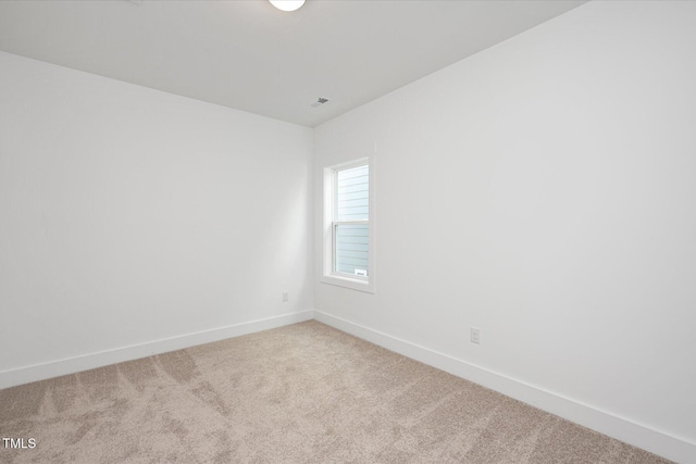 spare room with light colored carpet, visible vents, and baseboards