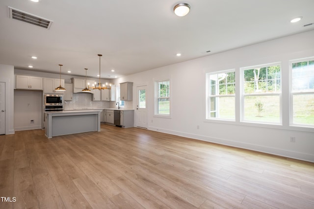 kitchen featuring stainless steel appliances, a kitchen island, visible vents, light countertops, and pendant lighting