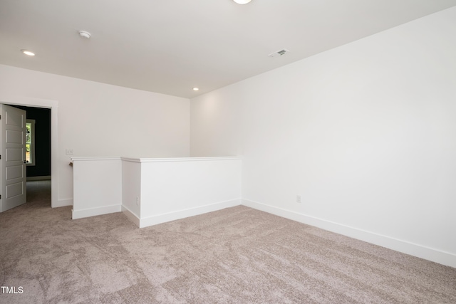 empty room featuring light colored carpet, visible vents, baseboards, and recessed lighting