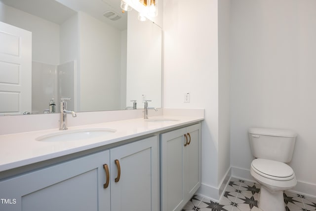 full bathroom with double vanity, a sink, toilet, and baseboards