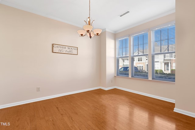 spare room with crown molding, wood-type flooring, and a chandelier