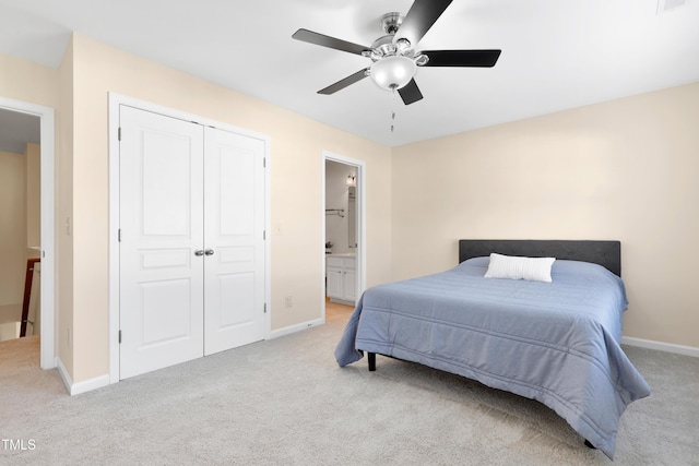 bedroom featuring ceiling fan, light colored carpet, ensuite bath, and a closet